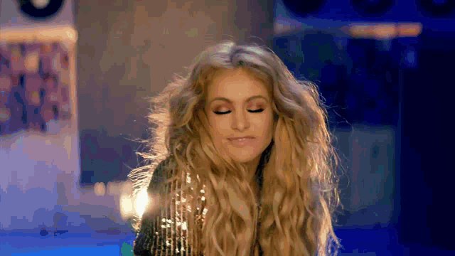 a woman with long blonde hair is wearing a sequined dress