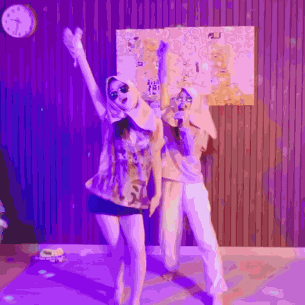 two women are standing next to each other in front of a purple wall .