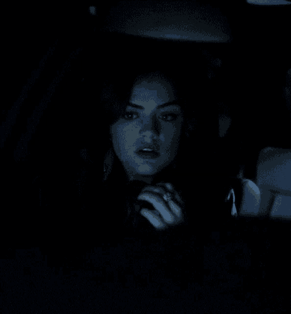 a woman is driving a car in the dark