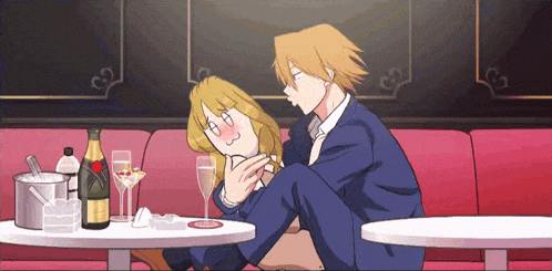 a man and a woman sit at a table with a bottle of champagne