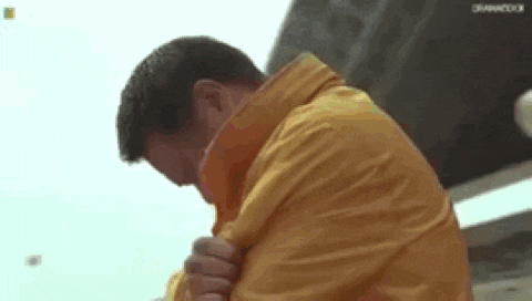 a man in a yellow jacket is standing on a bridge .