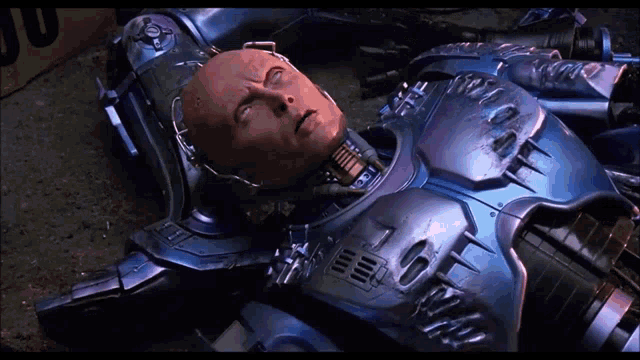a robot is laying on the ground with a yellow box in the background
