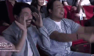 two men are sitting in a theatre with their arms outstretched .