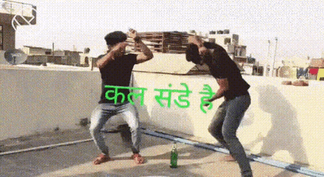 two men are dancing on a rooftop with a bottle of alcohol in the foreground