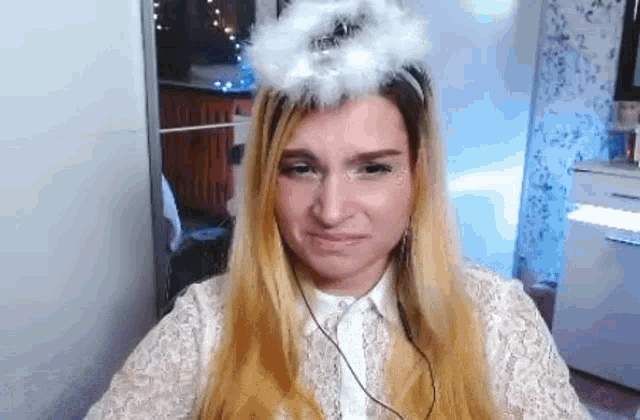 a woman is wearing a white angel wing on her head and making a funny face .