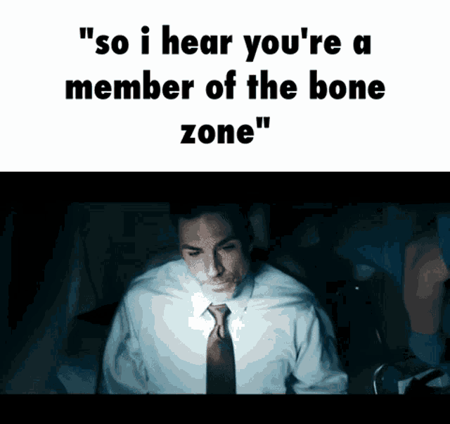 a man in a white shirt and tie is sitting in a dark room with a light on his face