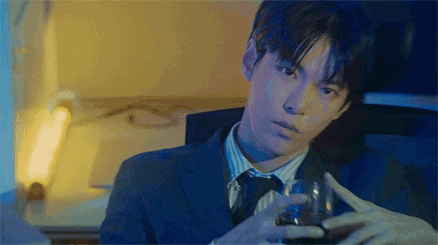 a man in a suit and tie holds a glass in his hand
