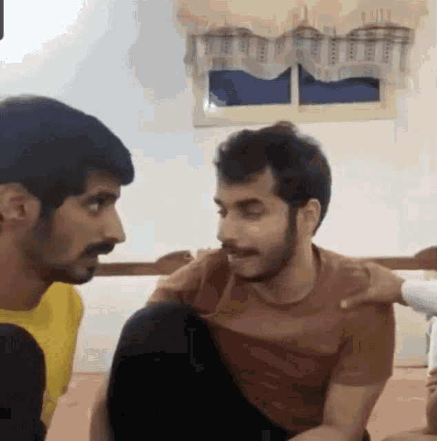 a man in a red shirt is talking to another man