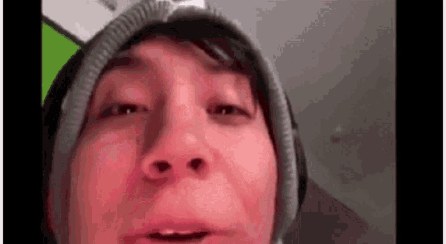 a close up of a person 's face wearing a beanie and making a funny face .