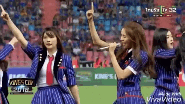 a group of women are singing into microphones on a field .