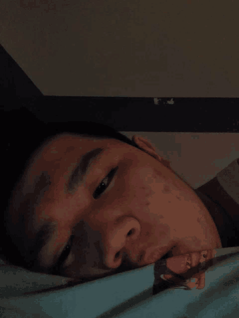 a young man laying in bed with his eyes closed and a spongebob shirt on