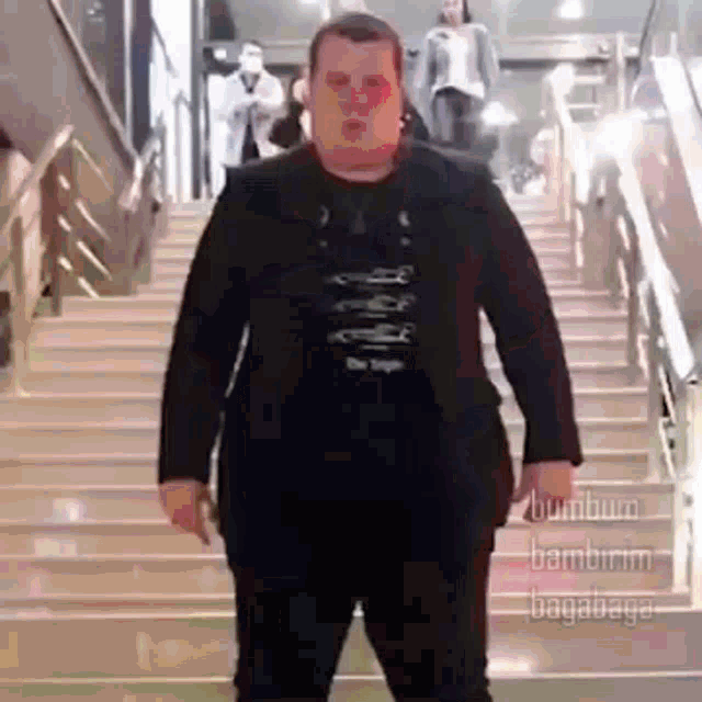 a man in a suit and black shirt is standing on a set of stairs .