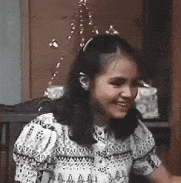 a young girl is sitting in a chair smiling .