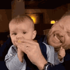a man is holding a baby who is eating a piece of food .