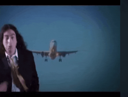 a man in a suit and tie stands in front of a plane