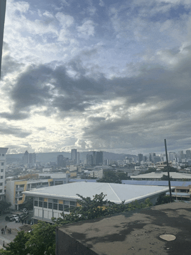 a view of a city from a rooftop with a cloudy sky