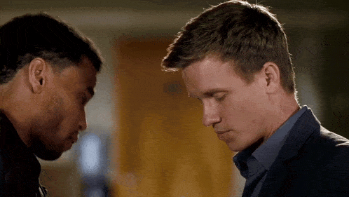 two men are touching their foreheads and looking down