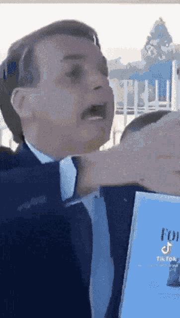 a man in a suit and tie is holding a book that says tiktok