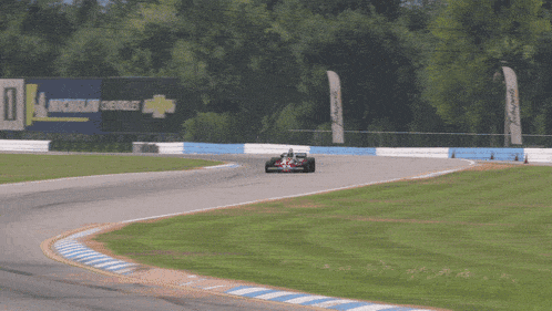a race car is going down a track with a michelin sign behind it