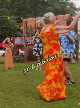a woman in a hawaiian dress is dancing with a sign that says go & fabulous on it