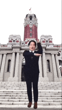 a man in a suit and tie is standing in front of a large building .
