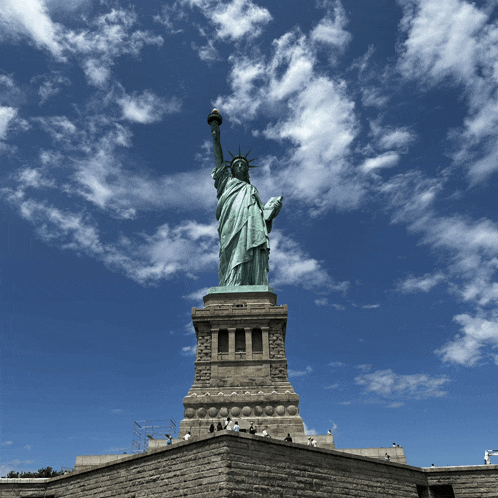 the statue of liberty stands tall against a blue cloudy sky