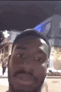 a man with a beard is making a funny face in front of a building at night .