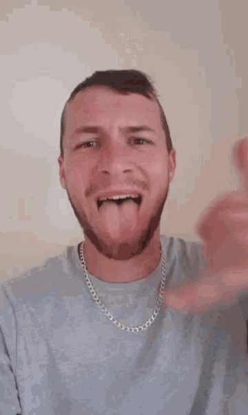 a man with a beard is sticking his tongue out and giving a thumbs up sign