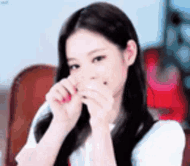 a woman with long black hair is making a heart with her hands .