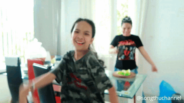 a girl in a camouflage shirt is dancing in front of a woman in a black shirt that says jordan