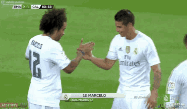 two soccer players shaking hands with one wearing a fly emirates jersey