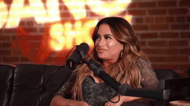 a woman sits in front of a microphone in front of a brick wall that says fail show