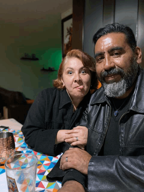 a man and a woman are posing for a picture and the woman is sticking her tongue out