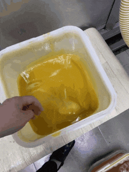 a person is reaching into a yellow container of liquid