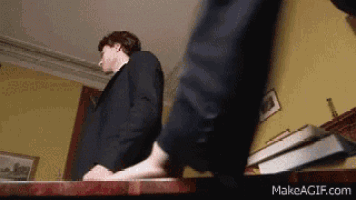 a man in a suit is standing on a table with a book on it .