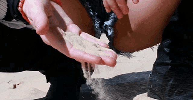a person is holding a handful of sand in front of their knee