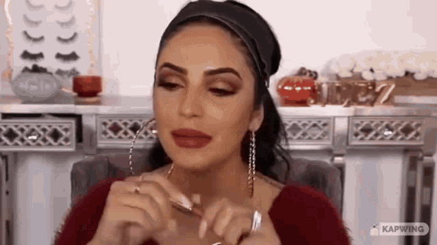 a woman is applying red lipstick to her lips while sitting in front of a mirror .