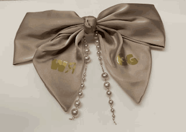 a bow with the letter g on it and pearls