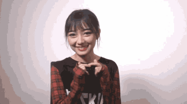 a girl wearing a black shirt with the word ski on it makes a heart shape with her hands