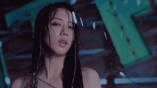 a woman with wet hair is standing in the rain looking at the camera .