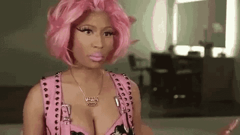a woman with pink hair and a necklace is wearing a pink vest and a pink wig .
