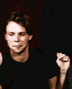 a man with a tattoo on his wrist is smiling and holding his fist up