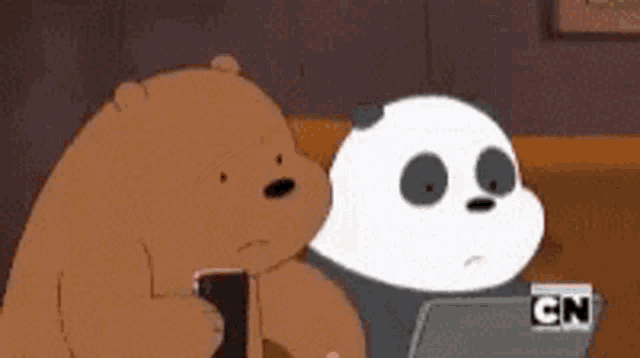 two bears are sitting next to each other and one is looking at a laptop .