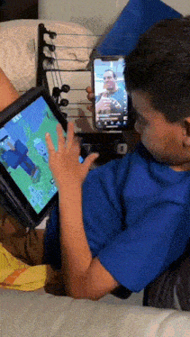 a boy in a blue shirt is playing a game on a tablet