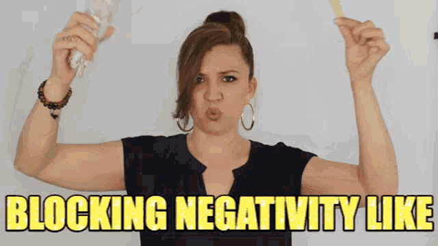 a woman is holding a stick and making a face with the words blocking negativity like below her
