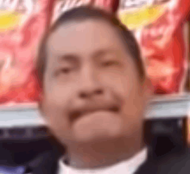 a man in a suit is making a funny face in front of a bag of chips .