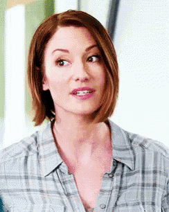 a woman with short hair is wearing a plaid shirt and making a funny face .