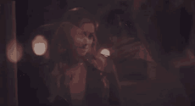a man and a woman are standing next to each other in a dark room and looking at each other .