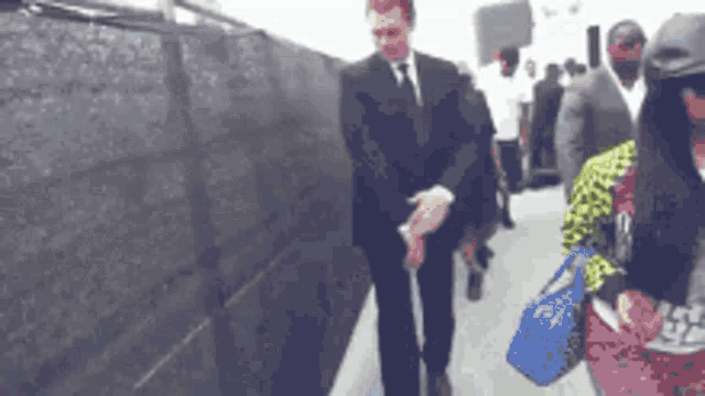 a man in a suit and tie stands next to a woman holding a blue purse