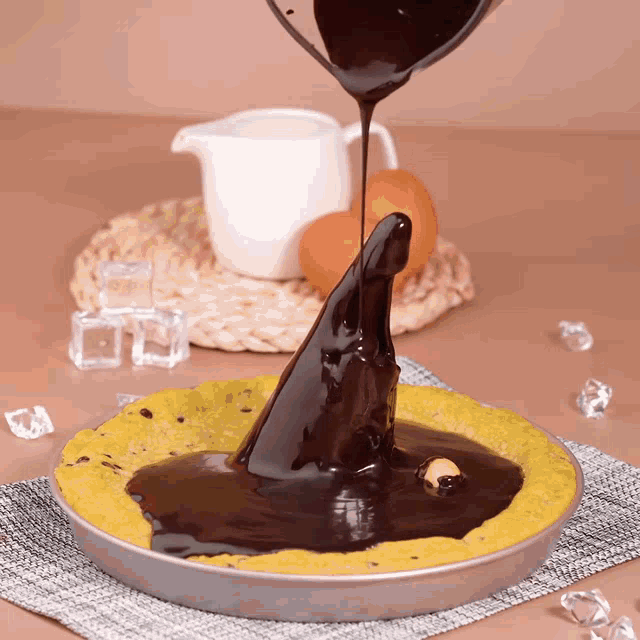a pie is being covered in chocolate sauce with ice cubes in the background